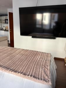 a bedroom with a bed with a large tv on the wall at Ribeira Penélope in Ribeira