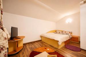 a bedroom with a bed and a desk with a television at Casa Valeria Voronet in Voronet