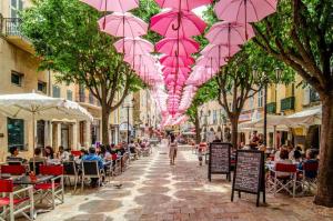 a street with pink umbrellas hanging from trees at L'Instant Parfumé in Grasse
