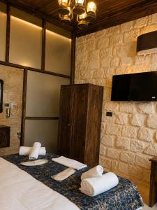 a bedroom with a bed with towels and a tv at Kasrı Hatun Konağı in Mardin