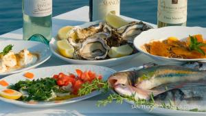 a table with plates of food with fish and vegetables at Li Teggi Turismo Rurale in San Teodoro