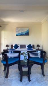 a bedroom with a bed with blue chairs and a table at Kirra's Beach House in Pulukan