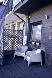 a patio with two white chairs and a table at Willa Sky in Jastrzębia Góra