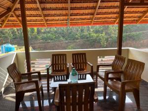 a porch with chairs and a table with a vase on it at Gramasiri Homestay in Sringeri