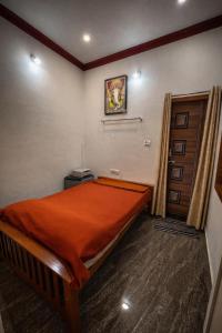 a bedroom with a large bed with an orange blanket at Gramasiri Homestay in Sringeri