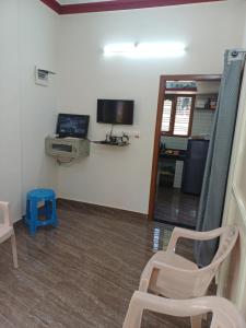 a room with a chair and a tv and a mirror at Gramasiri Homestay in Sringeri