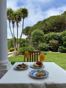 a table with two plates of food and two glasses of orange juice at Conjó - Golf & Beach Apartment Praia del Rey in Amoreira