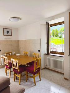 a dining room with a wooden table and chairs at NicoMeli Home in Dimaro