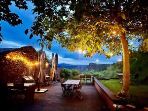 a wooden deck with a table and chairs and a tree at la Ferme de Vazerat in Massiac