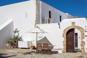 two chairs and an umbrella in front of a building at Al 583 di Lindos in Lindos