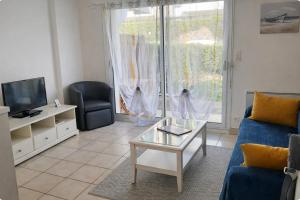 a living room with a blue couch and a tv at Centre ville de Sarzeau, appartement au calme avec jardinet et parking privé in Sarzeau