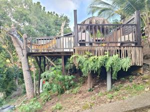 a wooden deck with a house on a hill at Cabanes rêve d'enfant in Les Anses-dʼArlets