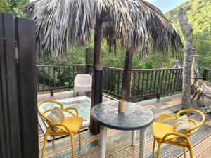a patio with a table and chairs on a deck at Cabanes rêve d'enfant in Les Anses-dʼArlets