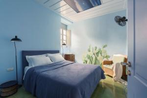 a blue bedroom with a bed and a chair at Cactus Hydra - Art Apartments in Hydra