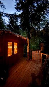a small red cabin with a bench on a deck at Dům ve stromech nad řekou in Moravecké Pavlovice