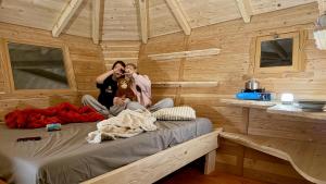 two people sitting on a bed in a cabin at Dům ve stromech nad řekou in Moravecké Pavlovice