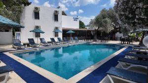a swimming pool with chairs and a building at Ali Baba Hotel Gümbet in Gümbet