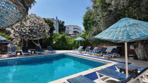 a swimming pool with chairs and umbrellas at Ali Baba Hotel Gümbet in Gümbet