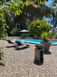 a swimming pool with two lounge chairs and an umbrella at L'Escapade in Cazouls-d Herault