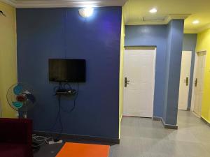 a room with a blue wall with a tv on it at Electra Serviced 1 Bedroom Apartment, Lagos in Iju Junction