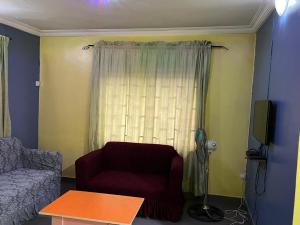 a living room with a red chair and a window at Electra Serviced 1 Bedroom Apartment, Lagos in Iju Junction