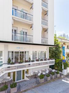 a hotel with tables and chairs in front of a building at Vibe Hotel in Cattolica