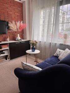 a living room with a blue couch and a brick wall at Apartament Szafir in Gdańsk