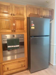 a kitchen with a stainless steel refrigerator and wooden cabinets at Private Rm3 with Queen bed in Elderslie +28 photos