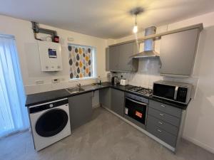 a kitchen with a sink and a stove and a microwave at Favour homes in Manchester