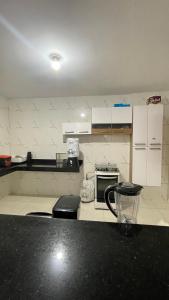 a kitchen with white cabinets and a black counter top at Villa Serrinha - Sitio Paraiso in Serrinha