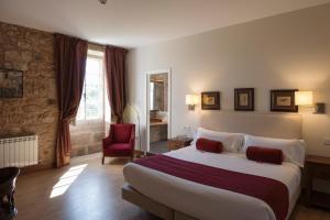 a bedroom with a large bed and a red chair at Hotel Pazo de Bieite in Boimorto