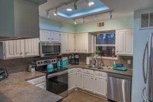 a kitchen with white cabinets and stainless steel appliances at Mariners Village Tranquil Condo in Seabrook