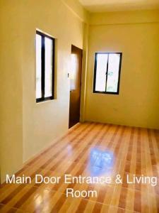 an empty room with a wooden floor and two windows at Mendoza's Apartment in Tuy