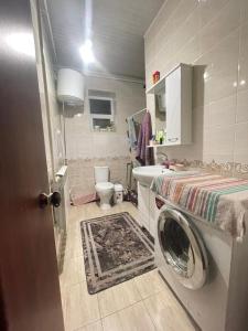 a bathroom with a washing machine and a toilet at Arlanguesthouse in Dzhangyaryk
