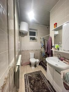 a bathroom with a white toilet and a sink at Arlanguesthouse in Dzhangyaryk
