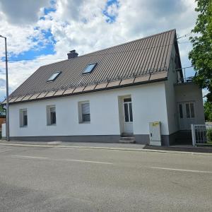 a white building with a metal roof on a street at Apartman Čardak in Gospić