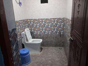 a bathroom with a toilet and a tiled wall at Shree krishn yatri nivas in Ellora