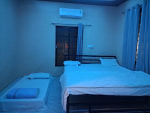 a bedroom with two beds and a window at Shree krishn yatri nivas in Ellora