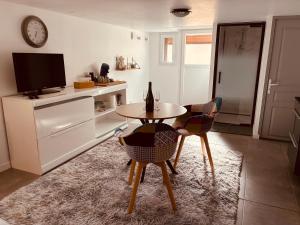 a living room with a table and chairs and a tv at Le Ptit Refuge d'Ay in Ay