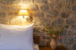 ein Schlafzimmer mit einem Kissen und einer Vase mit einer Blume in der Unterkunft Pyrgoi Theodorakaki: O Gerolimenas in Yerolimin