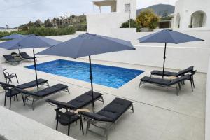 a group of chairs and umbrellas next to a pool at Sunny & Blue 2 in Parasporos
