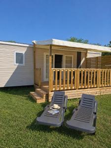 a deck with two chaise lounges and a house at Camping Le Chassezac in Sampzon