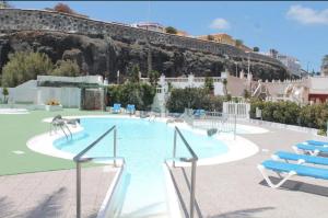 a large swimming pool with chairs and asevere at Apartamento Playa relax in La Estrella