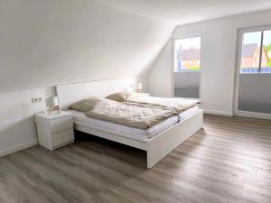 a white bedroom with a bed and a window at Ferienwohnung Heide in Walsrode