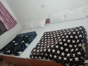 a bed with a black and white blanket on it at Punchkedar in Phata