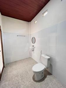 a white bathroom with a toilet and a mirror at KUTA GLORI Homestay in Kuta Lombok
