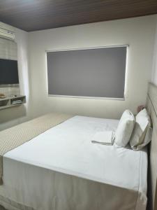 a bedroom with a large white bed with a window at Recanto Vila Madalena in Caçapava +21 photos