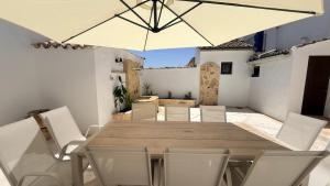 a wooden table with white chairs and an umbrella at La Casa del Rey Alhamar in Arjona