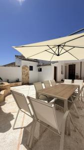 a wooden table with chairs and an umbrella on a patio at La Casa del Rey Alhamar in Arjona