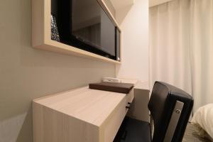 a room with a desk with a tv on the wall at Vessel Inn Shinsaibashi in Osaka